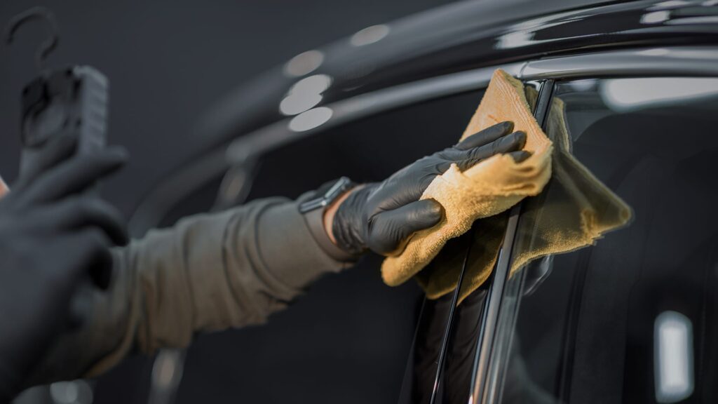 person wiping shiny black vehicle.